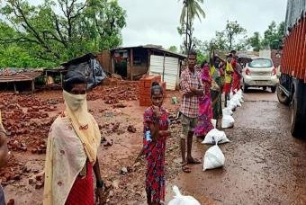 People brave the overcast weather to collect essential grocery kits