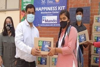A beneficiary child collects her Happiness Kit