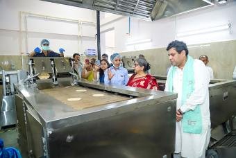 Shri Mukul Hasteer and Smt Reena Sharma understanding the cooking process explained by Akshaya Patra staff