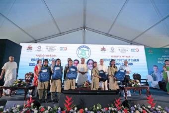 The beneficiaries are happy to receive school bags from the guests at the kitchen inaugural ceremony.